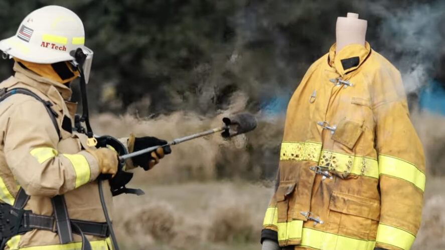 A person in yellow jacket holding fire hoses.