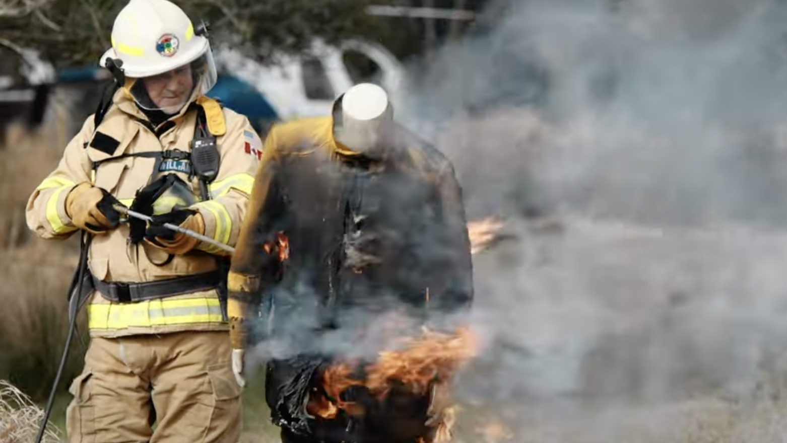 A fireman is standing next to a fire.