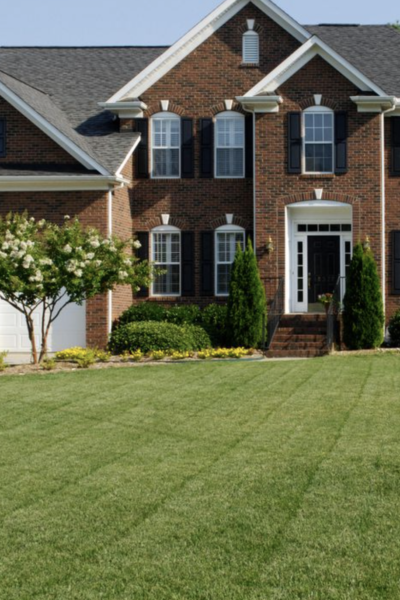 A large brick house with a lawn in front of it.