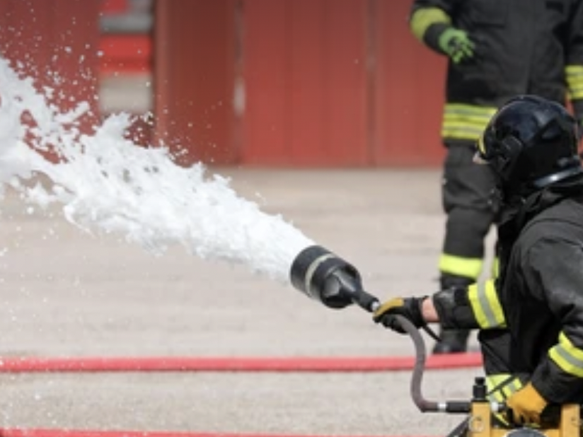 A fireman is spraying water from his hose.