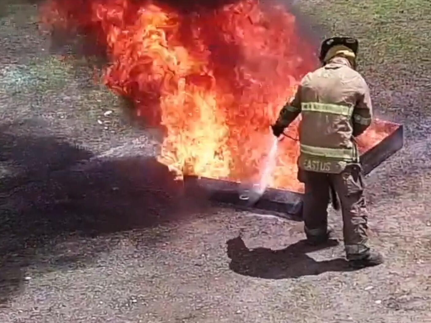 A fireman is standing in front of a fire.